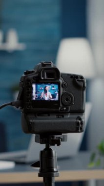 Dikey video: Seyircilerle konuşan profesyonel kamera kaydedicinin yakın çekimi. Ünlü sosyal medya etkileyicisi evde otururken internet video paylaşım platformları için video bloğu çekiyor