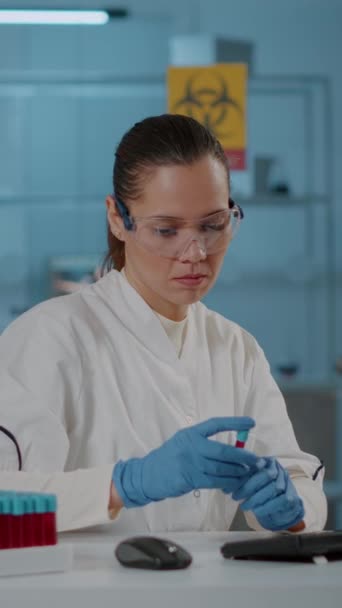 垂直ビデオ 女性科学者は 試験管内の液体を分析し 化学革新のためのコンピュータを使用しています 微生物学者は分析のためのフラスコを保持し 業界を発展させるためにモニターに取り組んで — ストック動画