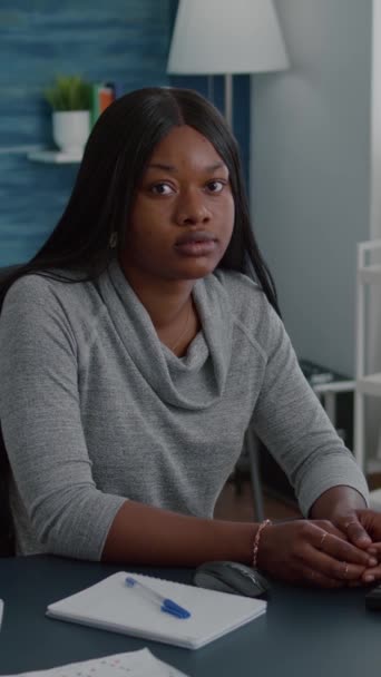垂直视频 一个快乐的黑人女性在家庭冷却的时候坐在客厅的桌子旁看着相机的肖像 在课本上工作的学生笑着学习浏览高中 — 图库视频影像