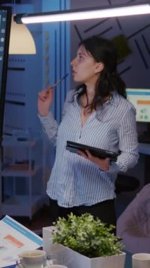 Dikey video: İşkolik odaklı işkadını, yönetim çözümüne işaret eden bir strateji belirterek, şirket işletme bürosunun toplantı odasında fazla çalışmanın izlenmesine dikkat çekti. Çok ırklı iş arkadaşları tartışıyorlar