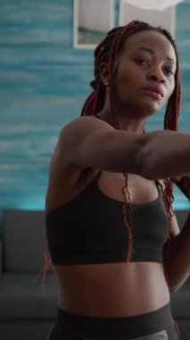 Verical video: Sağlıklı yaşam sporu eğitimi sırasında oturma odasında yoga halterleri kullanarak spor kıyafeti giyen zayıf fit bir kadın. Atletik yetişkin vücut kası çalışıyor.