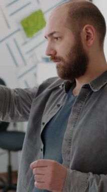 Dikey video: Masadaki kentsel projeyi tasarlamak için inşa modeline ve maketine bakan adam mimarı kapatın. Şablon planı ve çizimi ile inşaat düzeni tasarımı üzerinde çalışan bir inşaatçı.