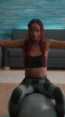 Verical video: Formda kadın antrenör kol kası egzersizleri yapıyor, halterleri ile yoga yapıyor, İsviçre topunun üzerinde oturuyor, oturma odasında pilates yapıyor, spor yapıyor. Zayıf yetişkin