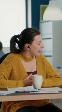 Startup office employee using laptop in video conference with clients and manager talking about marketing strategy. Casual business woman in group call discussing with remote coworkers about charts.