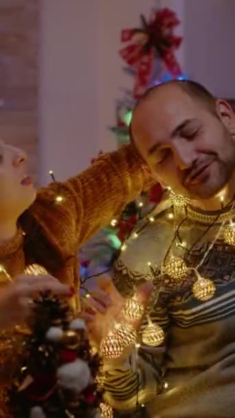 Dikey Video Noel Işıkları Dizisine Düğümlenmiş Şenlikli Çift Erkek Kadın — Stok video