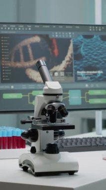 Dikey video: Hastane kliniğinde tıbbi araştırma ekipmanlarıyla laboratuvar masasında mikroskop. Günümüz teknolojisi, boş gezenler, pipetler ve bilimsel bilgisayarlar üzerinde bilimsel deneyler yapmak için kullanılır.