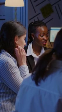 Dikey video: Siyah Afrika kökenli Amerikalı yönetici şirket fikirlerini araştırıyor yönetim sunum belgelerini kontrol ediyor ve akşam toplantı odasında fazla mesai yapıyor. Çeşitli etnik çeşitlilikte takım çalışması çözümü