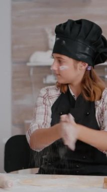 dikey video: Torunum Noel tatilini kutluyor geleneksel ev yapımı hamuru hazırlıyor xmas dekore edilmiş mutfakta zencefilli ekmek yapıyor. Çocuk aşçılık mutfağında oklavalı tatlı kullanıyor.
