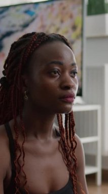 Verical video: Spor salonundaki spor antrenmanı sırasında yoga İsviçre topunda oturup sağlıklı yaşam tarzından keyif alan atletik zenci kadın portresi. Sıska formalı yetişkin spor giyim esneme hareketleri.