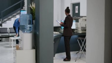 Kadın resepsiyonist, hastane resepsiyonunda muayene öncesi muayene belgelerini ve rapor formlarını inceliyor. Tesis lobisindeki kayıt masasında çalışıyorum..