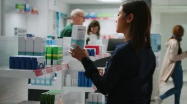 Eczane tezgahındaki Asyalı müşterilere sağlık ürünlerini açıklayan bir tıp çalışanı reçeteli ilaç ve takviyelerden bahsediyor. Eczane masasında uyuşturucu paketi bulundurmak..