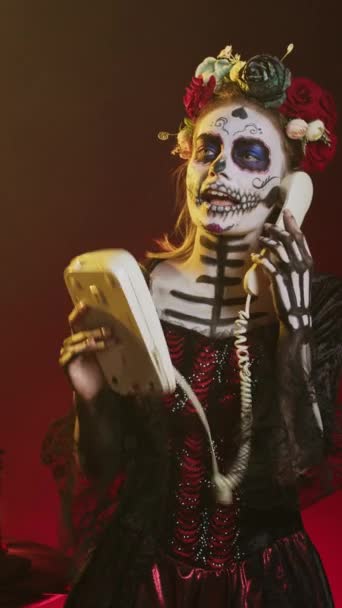 垂直ビデオ 電話に答えるために固定電話を使用して気味の悪い女性 メキシコのディオス ムエルトスの休日にオフィスコード電話を保持 カヴァレラ カトリーナのように死者の日を祝う — ストック動画