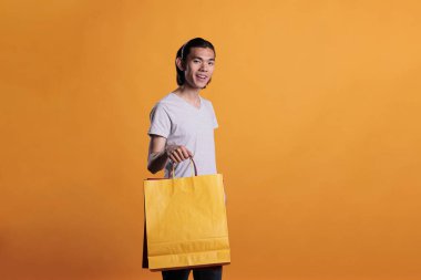 Kağıt alışveriş çantası taşıyan mutlu adam, mağaza satışı. Satın alma, alışveriş kolik ürünler, dükkândan paketler alan genç Asyalı insanlar, ticaret...