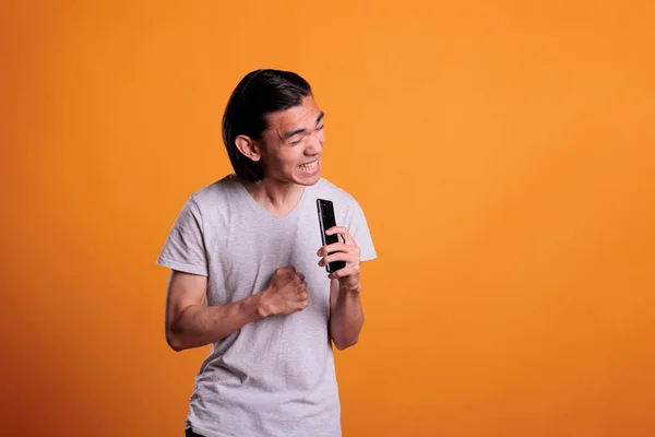 年轻的亚洲人唱卡拉Ok 鬼鬼祟祟的 用智能手机作为话筒 歌手练习唱歌 青少年拿着手机作为话筒 有创意的爱好 有趣的休闲活动 — 图库照片