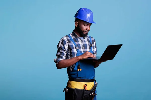 노동자 노트북 컴퓨터를 사용하여 유니폼 직업적 감독푸른 배경에 컴퓨터를 사용하면서 — 스톡 사진