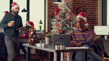 Noel Baba şapkalı çeşitli meslekdaşlar kış tatili sezonunda şenlikli ofiste dizüstü bilgisayarla çalışıyorlar. İş arkadaşları bilgisayar başında takım çalışması yapıyor, Noel arifesini kutluyorlar..