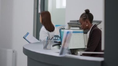 Diverse medical staff working at hospital reception counter, helping senior man with checkup appointment and healthcare insurance. Nurse and receptionist using report papers at registration counter.