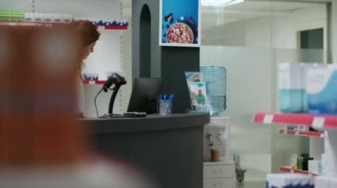 Eczacı kadın eczacı eczane tezgahında ilaç kutularını tarıyor, müşterilerin ilaç ve ilaç almasına yardım ediyor. Eczane masasında ilavelerle çalışan bir çalışan..