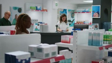 Afrikalı Amerikalı müşteriler eczaneden ilaç almak için temassız ödeme yaparak tıbbi ürünler alıyorlar ve kredi kartıyla ödüyorlar. İlaç almak için eczanede oturmak..