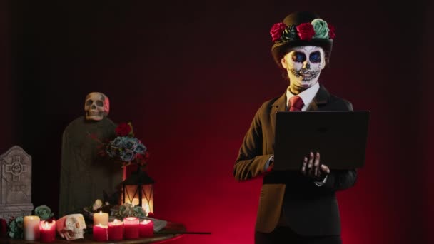 死の女神は スーツと帽子のハロウィンの衣装で聖なるサンタのマエルテを祝う メキシコの儀式のDios Los Muertos上のラップトップでインターネットサーフィン ワイヤレスPc上のウェブサイトを見て — ストック動画