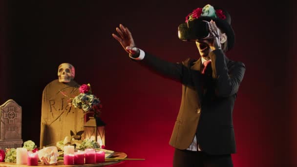 スタジオで人工知能を搭載したVrヘッドセットを使用して ハロウィンのお祝いに仮想現実メガネを保持する女性モデル ディオス ムエルトスの儀式で聖なるカヴァレラのカトリーナのように見える — ストック動画