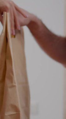 Dikey video: POS terminal servisini kullanarak akıllı saatle irtibatsız ödeme yapan iş kadını görüntüsü. Teslimatçı adam öğle yemeği siparişini şirkette getiriyor.