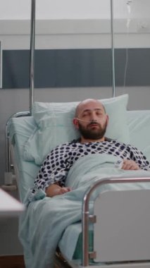 Dikey video: Pratisyen asistan hasta yatağını hastalığın iyileşme sürecinde hastane koğuşunda çalışan hastalık semptomlarını izlemesi için ayarladı. Hastanedeki hastada solunum bozukluğu var.