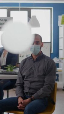 Küresel salgın sırasında Coronavirus enfeksiyonuna karşı maske takan işadamının dikey video portresi. İş projesinde çalışan takım çalışanları