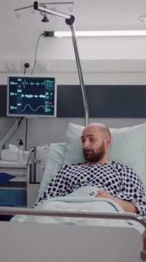 Dikey video: Afro-Amerikalı doktor hastane koğuşunda çalışan hastalık semptomlarının izlenmesi üzerine tıbbi uzmanlık yazıyor. Asistan kadın tedavi sırasında hastalık hapı alıyor.