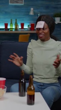 Dikey video: Bir grup çok ırklı insan birlikte zaman geçirerek masa oyunu oynarken eğleniyor. Yaratıcı arkadaşlar gece geç saatlere kadar oturma odasında takılıyor.