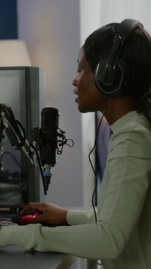 Dikey video: Afro-Amerikan Esport 'un arka plan görüntüleri kulaklık takarak sanal rekabet kaybediyor. Güçlü bilgisayarda yeni grafiklerle çevrimiçi video oyunları yayınlayan profesyonel oyuncu.