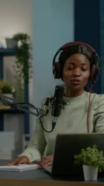 Dikey video: Afrikalı sosyal medya kadını Youtube kanalı için mikrofon kayıt podcast 'inde video kamera kullanarak konuşuyor. Çevrimiçi şov canlı yayın internet yayın sunucusu