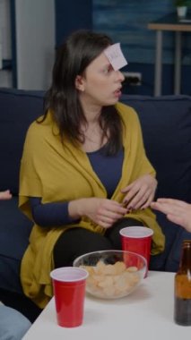 Dikey video: Eğlence oynarken eğlenen karışık ırktan insanların oluşturduğu bir grup. Bilin bakalım kim alnına yapışkan notlar iliştirdi? Yaratıcı arkadaşlar gece geç saatlerde takılıyorlar.