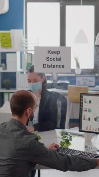 縦型ビデオコロナウイルスの感染を防ぐために保護面マスクを着用した新しい営業所でのロックダウン後に働く間 財務グラフィックスを分析するビジネス関係者 チームは社会を維持する — ストック動画
