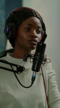 Dikey video: Afrikalı vlogger video blogu ev stüdyosu podcast 'inde modern ekipmanlarla akıllı telefon kullanıyor. Medya yıldızı yayın için kameraya bakıyor ve teknolojiyi kullanarak eğleniyor.