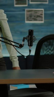 Dikey video: Rahat bir stüdyoda çalışan Afrikalı vlogger 'ın portresi, kameraya gülümsüyor ve yeni bir podcast şovu başlatmaya hazır. Çevrimiçi prodüksiyon internet yayınları sunucunun web içeriğini gösteriyor