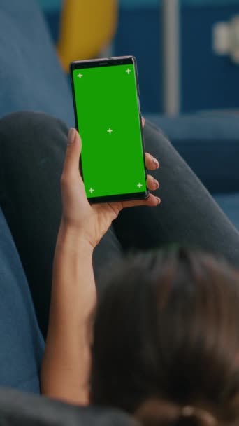 垂直视频 自由自在地躺在沙发上 在智能手机上安装有模拟绿色屏幕彩色键垂直显示的在线视频 使用隔离触摸屏装置进行社交活动的妇女 — 图库视频影像