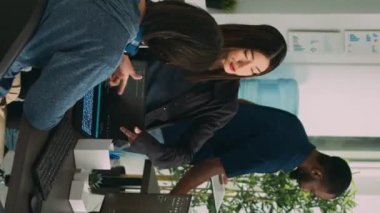 Dikey video: Yapay zeka bulut programcılarından oluşan Asyalı bir ekip ajans ofisinde programlama hakkında konuşuyor. Terminal pencere sunucusunda kod derleme, algoritma geliştirme üzerine takım çalışması.