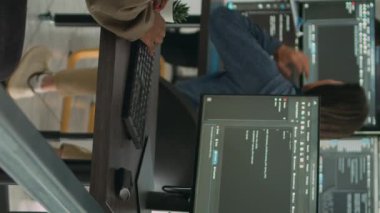 Dikey video: Uygulama yazılım geliştirici daktilo makinesi öğrenme uygulaması kodunu bilgisayarda, büyük bir veri şirketinin ofisinde masasında oturuyor. Siber güvenlikte yeni program arayüzü üzerinde çalışan bulut programcısı