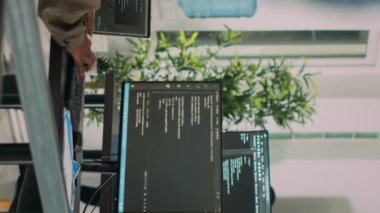 Dikey video: Afrika kökenli Amerikalı bulut programcılarından oluşan bir ekip programlama derleme kodları hakkında konuşuyor, yeni kullanıcı arayüzü geliştirme üzerinde çalışıyor. Sunucu algoritmaları geliştirmek için takım çalışması yapan kodcular.