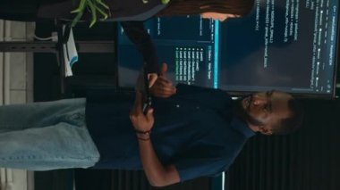 Dikey video: Yazılım programcıları büyük ekrandaki ve tabletteki algoritmalardan bahsederek html betik dilini analiz ediyorlar. Sistem mühendislerinden oluşan bir ekip terminal penceresinde, sunucuda veritabanını tartışıyor
