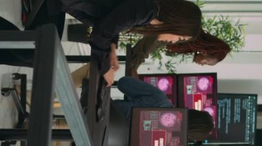 Dikey video: Sistem mühendislerinden oluşan bir ekip web sunucusunu hackleyerek, ofisteki birden fazla monitördeki kritik hatayı okuyor. Çeşitli yazılım geliştiricileri hackleme sorununu çözmeye çalışıyor, güvenlik duvarı güvenliği