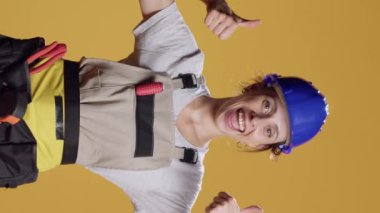 Dikey video: Stüdyoda onay veren ve kamerada onaylanan kadın inşaat işçisinin portresi. Kadın inşaatçı hoşlanma ve memnuniyet jesti, iyi bir yenileme çalışması.