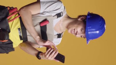 Dikey video: İnterneti taramak ve yenilenme ilhamı bulmak için akıllı telefon kullanan kadın mühendisin portresi. Alışılmadık bir işi olan kendine güveni olan biri, dekonstrüksiyon çalışmasıyla güçlenmiş hissediyor..