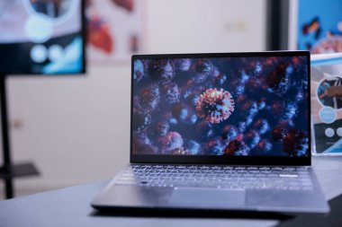 Virüsün mikroskobik görüntülerini gösteren bilgisayar ekranını kapat. Tıbbi merkezdeki laptopta görülen kötü huylu mikroorganizma hücresi örnekleri. Masada Coronavirus resimleri olan taşınabilir bilgisayar var..