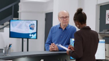 Afro-Amerikalı resepsiyonist hastane kayıt bölümündeki eski ptient ile raporlar hakkında notlar alıyor. Kadın resepsiyonda kıdemli bir adamla konuşuyor, sağlık kontrolü randevusu alıyor..