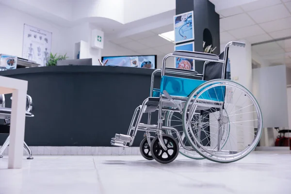 Wheelchair next to reception desk in family waiting area of medical clinic building. Patient admission area at entrance of hospital with furniture and medical equipment.