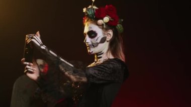 Cep telefonuyla video oyunu oynayan ürkünç genç kadın Dios de los Muertos kutsal geleneğinde cep telefonu kullanıyor. Santa Muerte modeli korkunç Meksika festivalinde eğleniyor. El kamerasıyla..