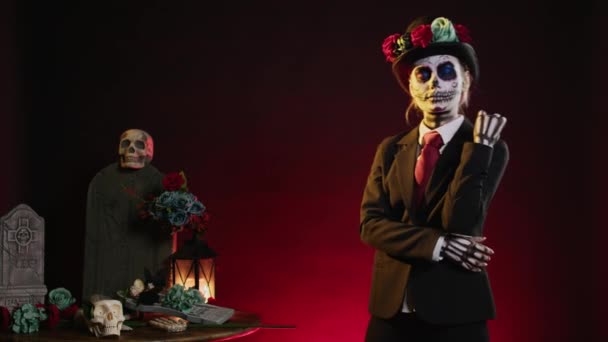 スーツと帽子を身に着けている神秘的な祭りの頭蓋骨のボディアート スタジオでDios Los Muertosを祝うサンタ マエルテとCavaleraカトリーナ 神聖なメキシコの実体のように見える女性 — ストック動画