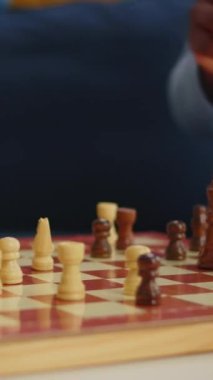 Dikey video: Siyah kadının satranç taşlarını taşıdığı ve arkadaşlarıyla boş zaman geçirdiği yakın çekim. Bir grup insan evlerinde eğleniyor oyun oynuyorlar, çeşitli kadınlar var.